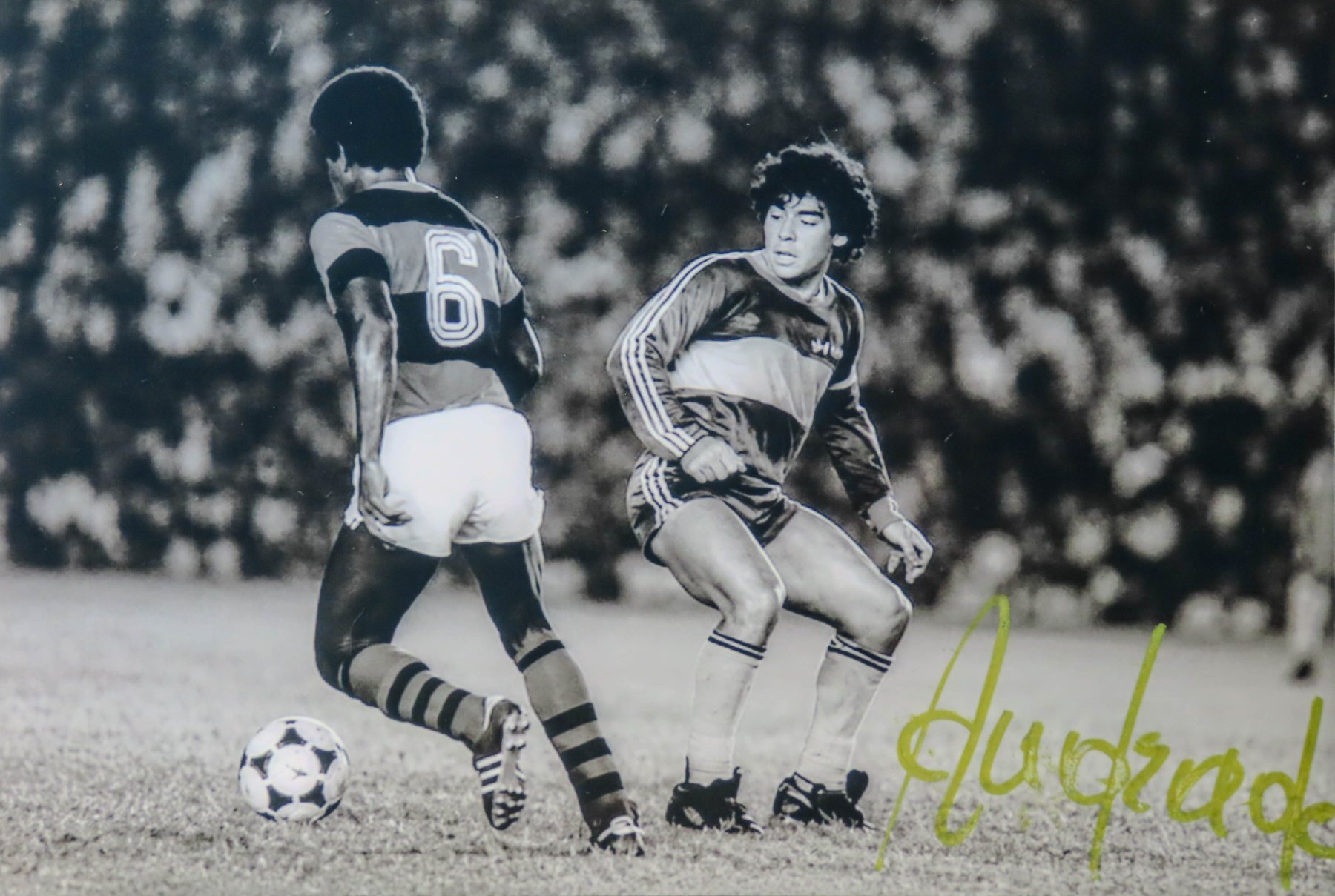 Fotografia em preto e branco que registra um duelo entre Andrade (camisa 6 do Flamengo) e Diego Maradona (Boca Juniors) em confronto realizado em 1981 - autógrafo manual
